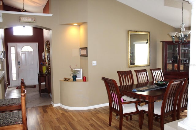 dining area with hardwood / wood-style flooring, a notable chandelier, and vaulted ceiling