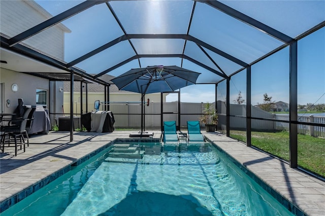 view of swimming pool featuring a lawn, glass enclosure, and a patio area