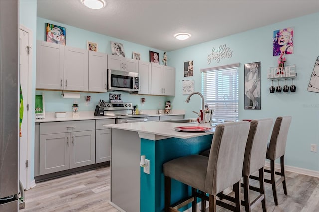 kitchen featuring appliances with stainless steel finishes, light hardwood / wood-style flooring, a kitchen island with sink, and a breakfast bar area