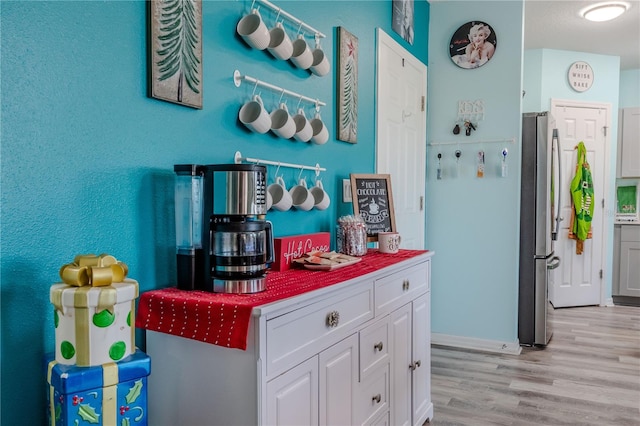 kitchen with white cabinets, stainless steel fridge, and light hardwood / wood-style floors