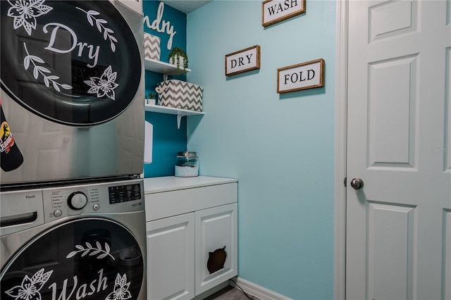 laundry room featuring cabinets and stacked washer / dryer