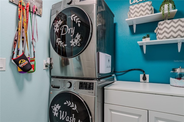 washroom featuring stacked washer and dryer and cabinets