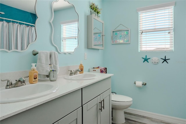 bathroom featuring a wealth of natural light, toilet, vanity, and hardwood / wood-style flooring