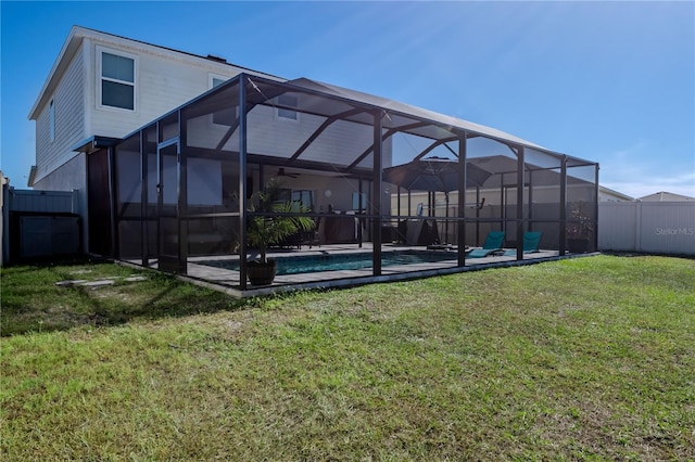 rear view of property featuring a lawn, glass enclosure, and a fenced in pool