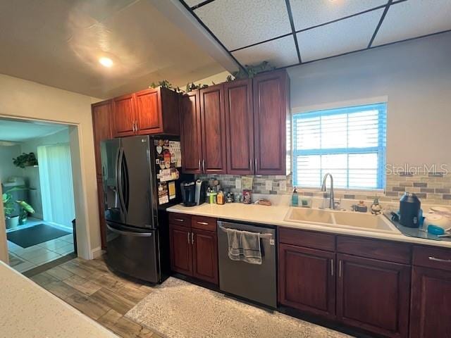 kitchen featuring light wood-type flooring, backsplash, stainless steel dishwasher, sink, and refrigerator with ice dispenser