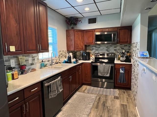 kitchen with decorative backsplash, sink, light wood-type flooring, and stainless steel appliances