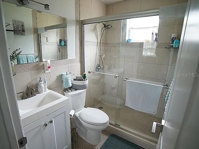 bathroom with walk in shower, backsplash, toilet, vanity, and tile walls