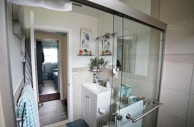 bathroom featuring vanity, walk in shower, and tile walls