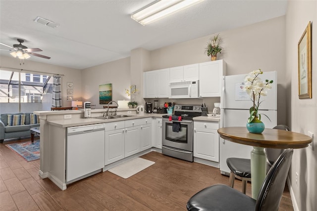 kitchen featuring kitchen peninsula, dark hardwood / wood-style flooring, white appliances, sink, and white cabinets