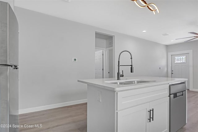 kitchen featuring appliances with stainless steel finishes, light wood-type flooring, a kitchen island with sink, sink, and white cabinets