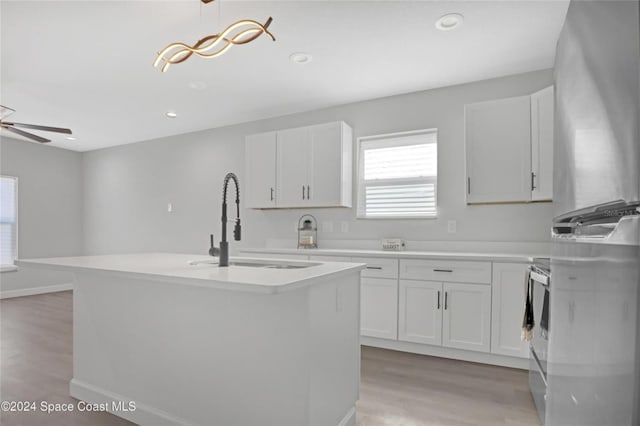 kitchen with white cabinets, pendant lighting, and light hardwood / wood-style floors