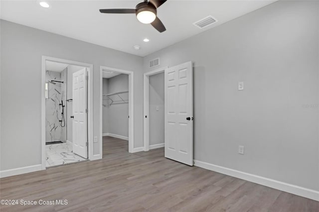 unfurnished bedroom with ensuite bathroom, ceiling fan, a spacious closet, light hardwood / wood-style floors, and a closet