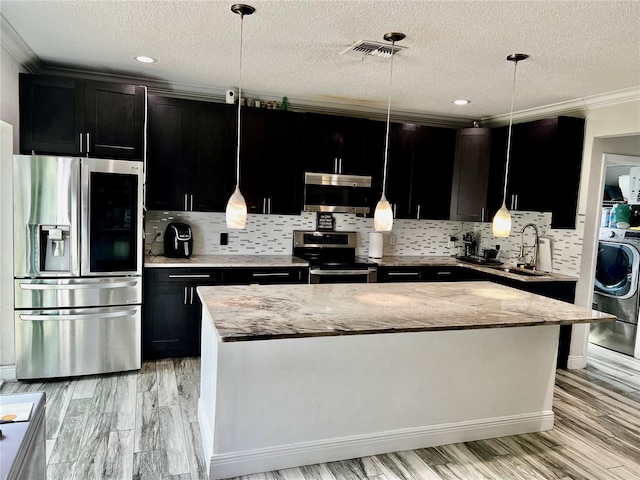 kitchen with decorative light fixtures, light stone countertops, and stainless steel appliances