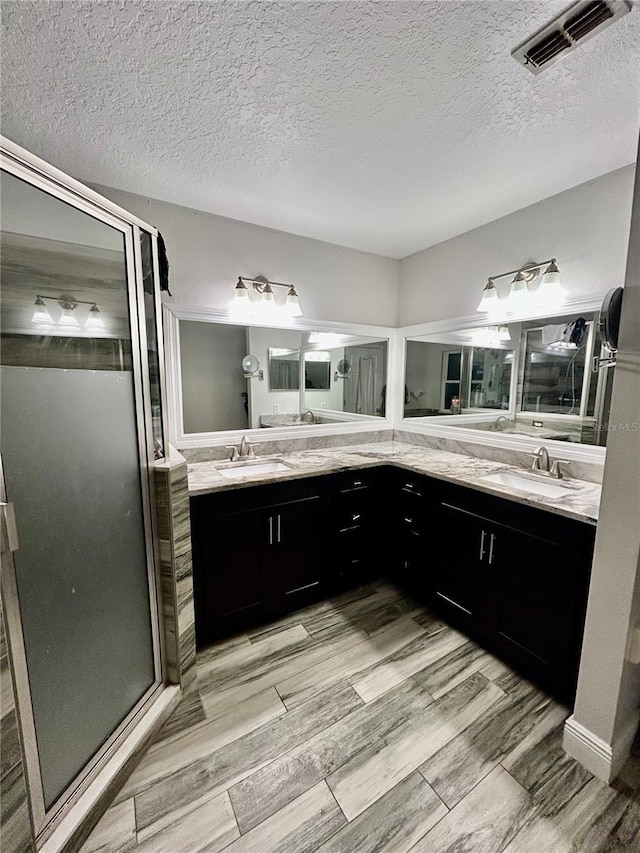 bathroom with vanity, a textured ceiling, hardwood / wood-style flooring, and an enclosed shower