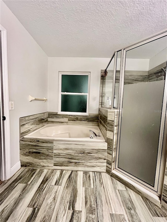 bathroom with hardwood / wood-style floors, a textured ceiling, and independent shower and bath