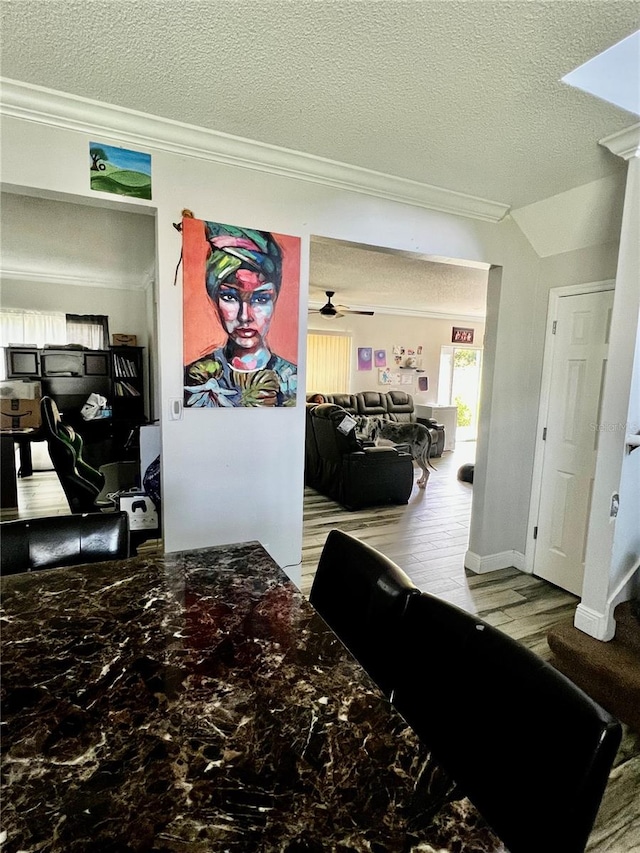 corridor featuring a textured ceiling, light hardwood / wood-style floors, vaulted ceiling, and ornamental molding