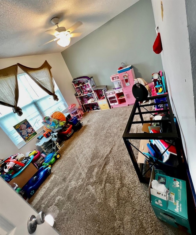 recreation room with carpet flooring, ceiling fan, and a textured ceiling