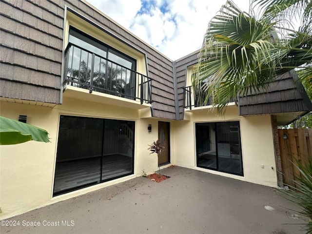 rear view of property featuring a patio area and a balcony