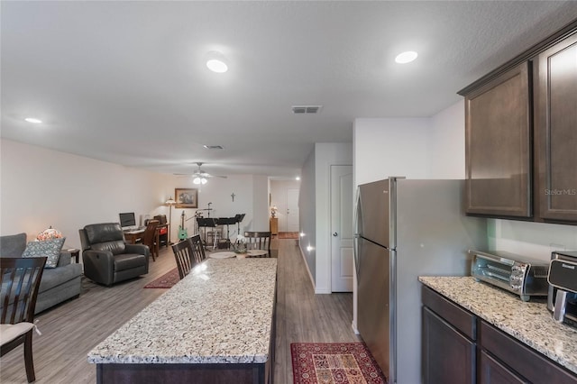 kitchen featuring hardwood / wood-style flooring, dark brown cabinets, and a center island