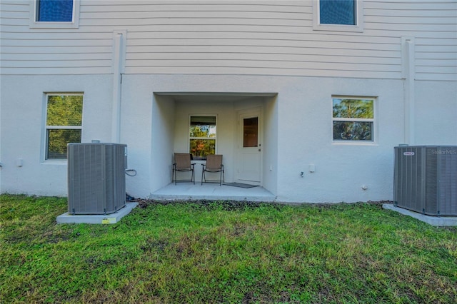 view of exterior entry with a yard and central AC