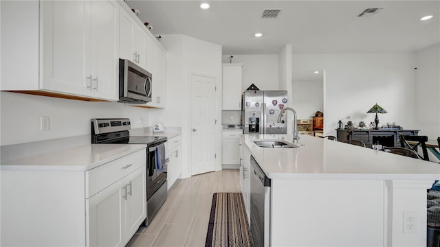 kitchen featuring sink, a center island with sink, appliances with stainless steel finishes, and white cabinetry