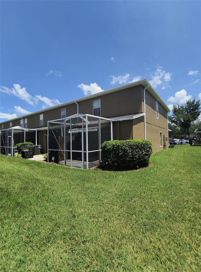 rear view of property with a yard and glass enclosure