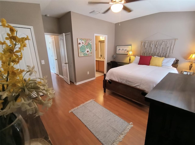 bedroom featuring connected bathroom, light hardwood / wood-style floors, vaulted ceiling, and ceiling fan