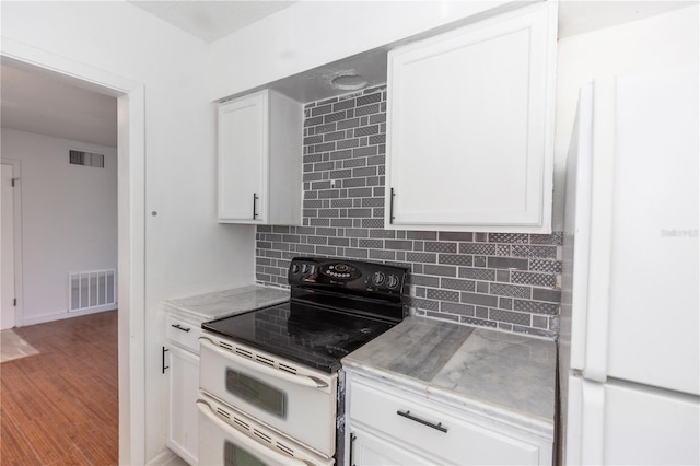 kitchen featuring light stone countertops, backsplash, wood-type flooring, white cabinets, and white electric range