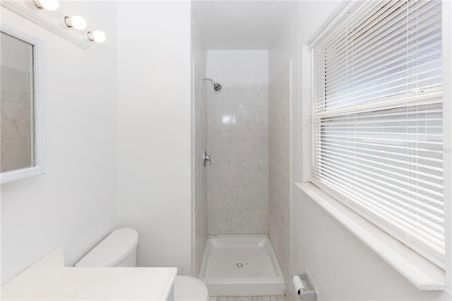 bathroom featuring vanity, toilet, and tiled shower