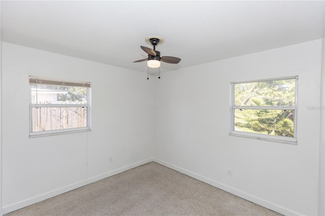 unfurnished room featuring plenty of natural light, ceiling fan, and light colored carpet