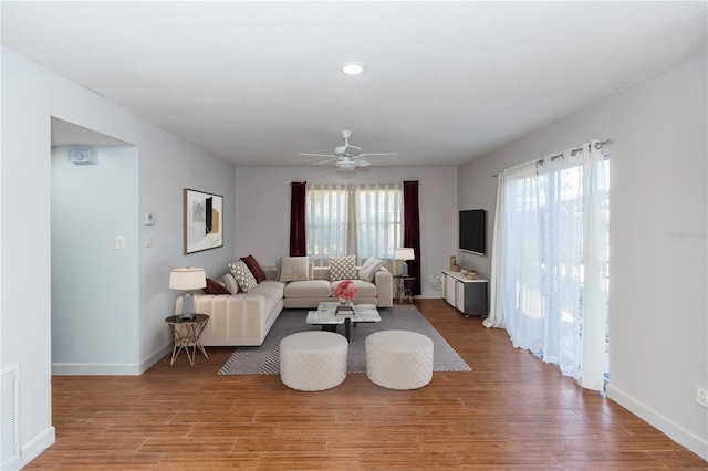 living room with light wood-type flooring, ceiling fan, and a healthy amount of sunlight