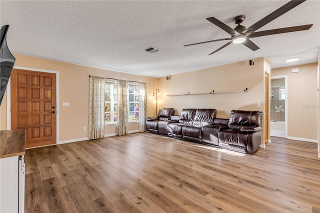 living room with a textured ceiling, light hardwood / wood-style flooring, and ceiling fan