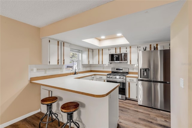 kitchen with white cabinets, appliances with stainless steel finishes, kitchen peninsula, and sink