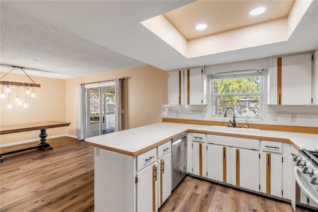 kitchen with white cabinetry, sink, stainless steel appliances, kitchen peninsula, and light hardwood / wood-style floors