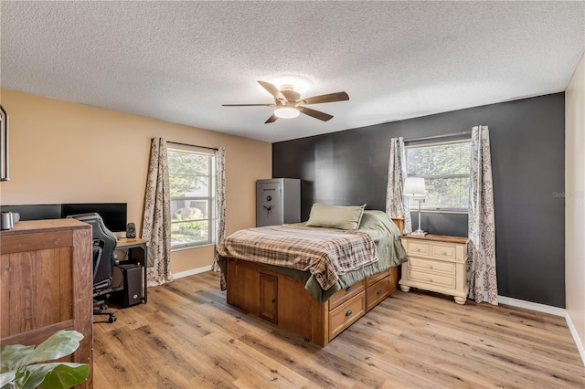 bedroom with multiple windows, a textured ceiling, light hardwood / wood-style flooring, and ceiling fan