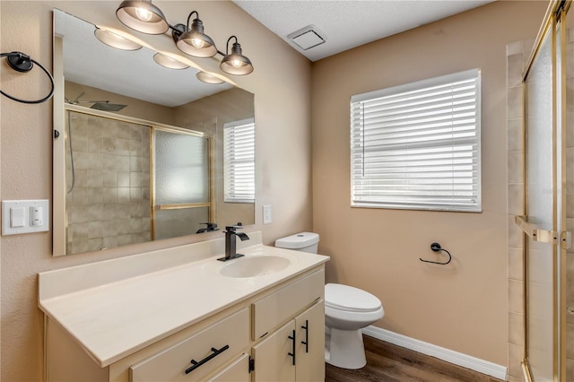 bathroom with vanity, a textured ceiling, wood-type flooring, toilet, and a shower with shower door