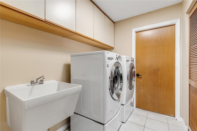 washroom featuring light tile patterned flooring, cabinets, sink, and washing machine and clothes dryer