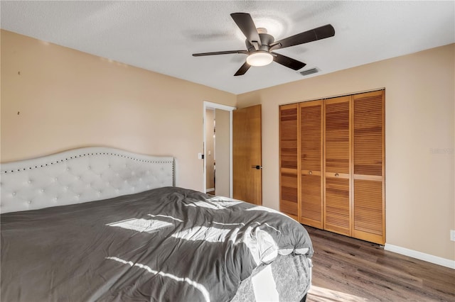 bedroom with a textured ceiling, a closet, hardwood / wood-style flooring, and ceiling fan