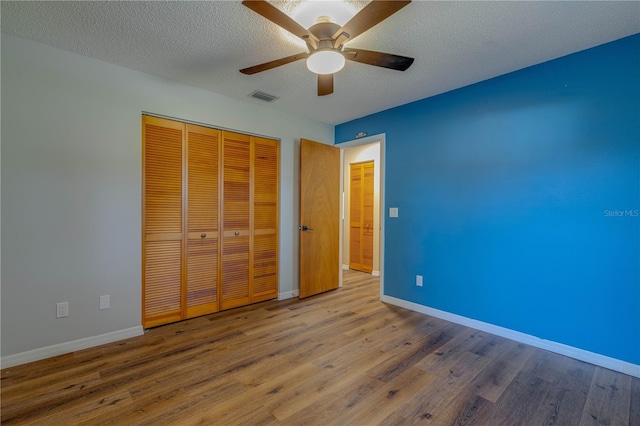 unfurnished bedroom featuring ceiling fan, a closet, a textured ceiling, and hardwood / wood-style flooring