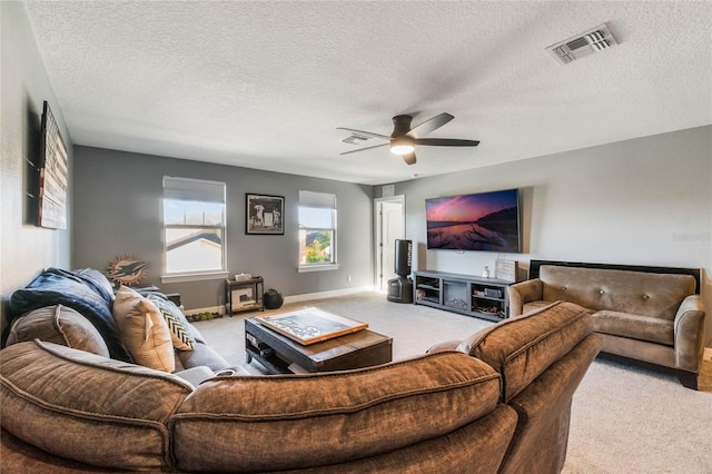 carpeted living room featuring ceiling fan and a textured ceiling