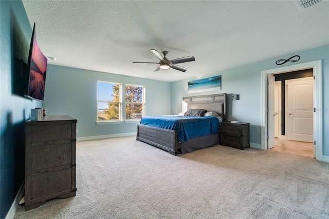 carpeted bedroom featuring ceiling fan and a textured ceiling