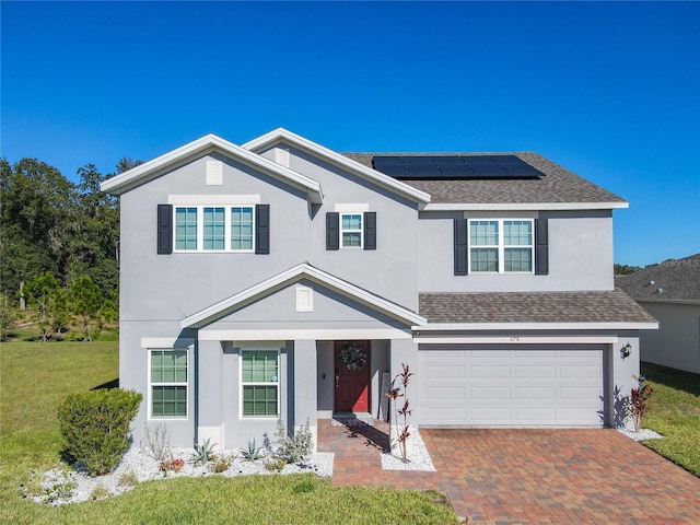 front of property featuring solar panels, a garage, and a front yard