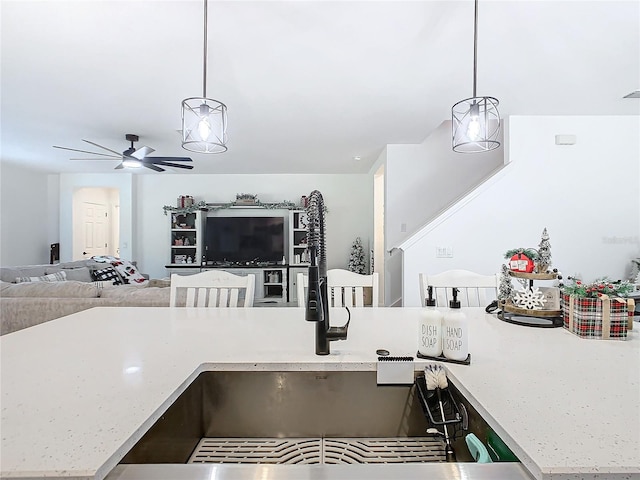 kitchen with pendant lighting, ceiling fan, and light stone counters