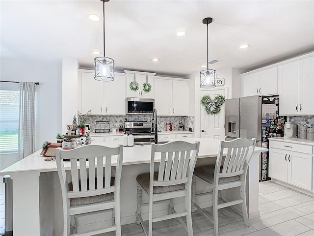 kitchen featuring appliances with stainless steel finishes, decorative light fixtures, and white cabinetry