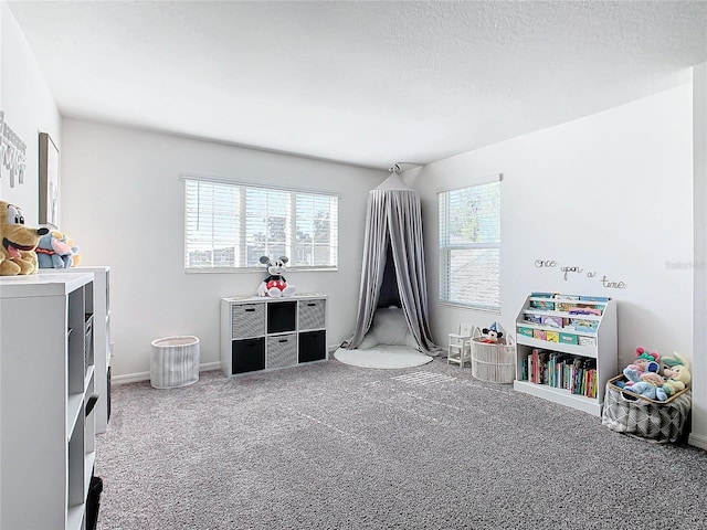 recreation room with a textured ceiling, carpet floors, and plenty of natural light