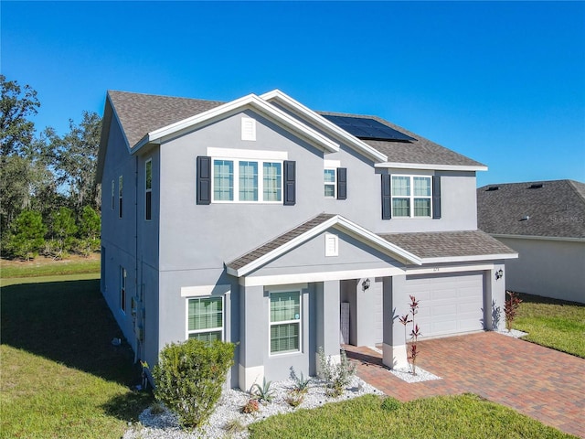 front facade featuring solar panels, a garage, and a front lawn