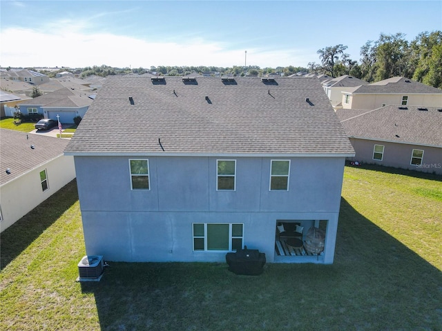 rear view of property featuring a yard and central AC