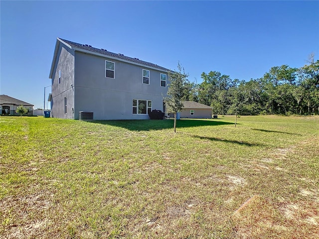 rear view of house with cooling unit and a lawn