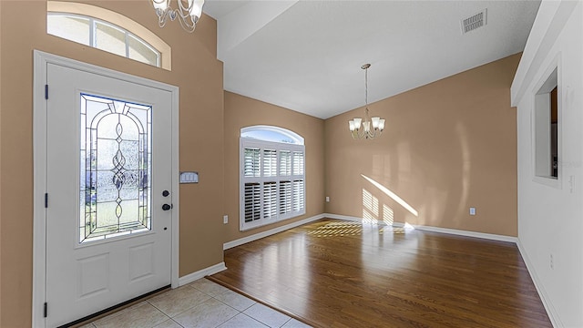 entryway with light hardwood / wood-style floors, a wealth of natural light, and a notable chandelier