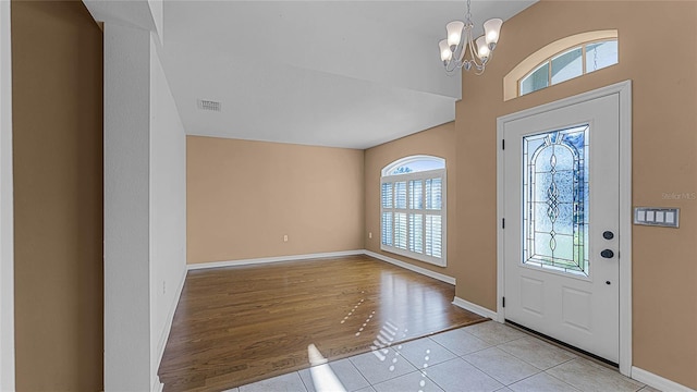 foyer with plenty of natural light, a chandelier, and light wood-type flooring